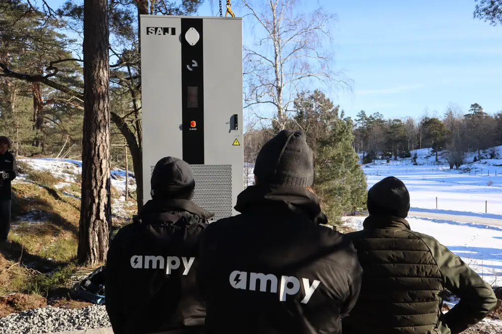 Tre elektriker från Ampy som står framför ett stort, nyinstallerat SAJ-solcellsbatteri.