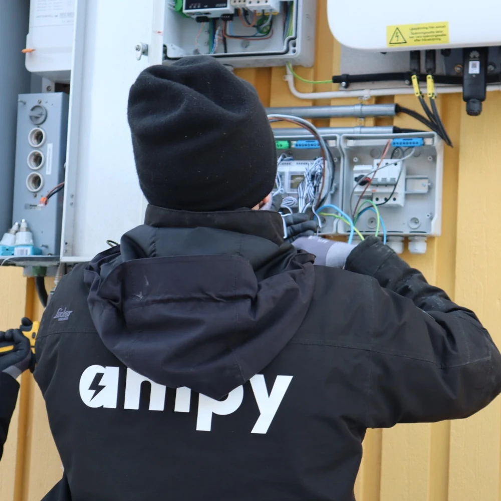 En certifierad elektriker som fokuserat arbetar med en elinstallation av ett hembatteri.