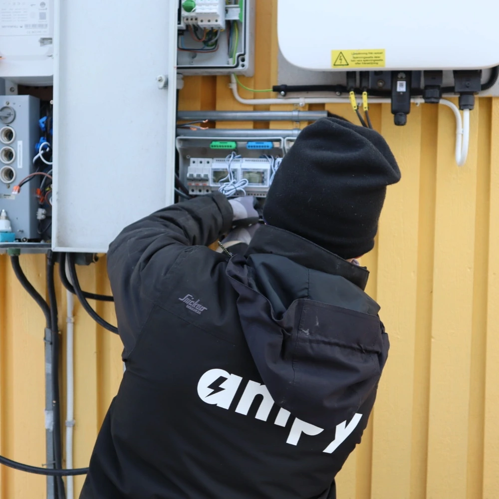 En elektriker med Ampy-logotyp som arbetar vid installation av ett batterisystem.