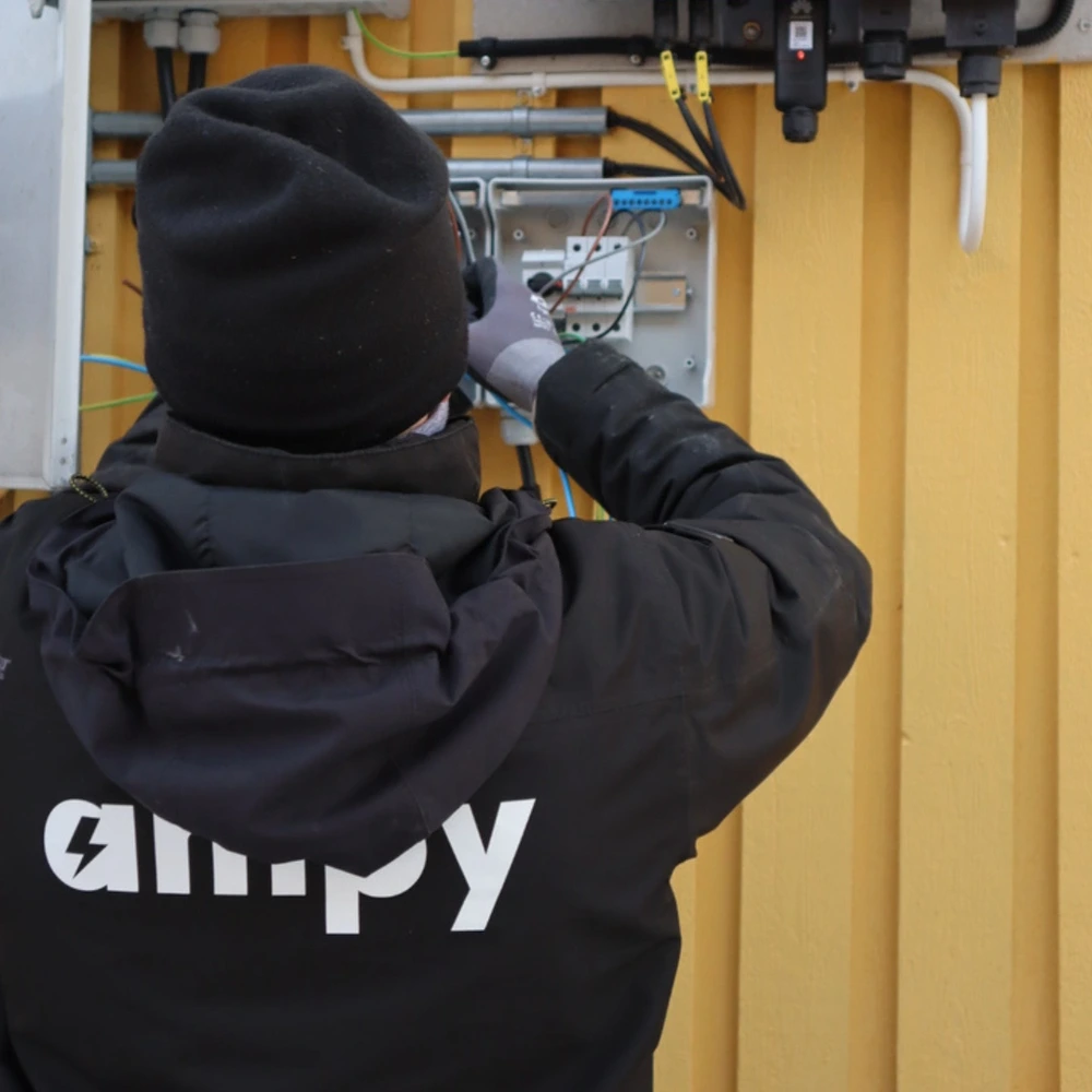 En Ampy-elektriker som monterar och ansluter en växelriktare på en vägg.
