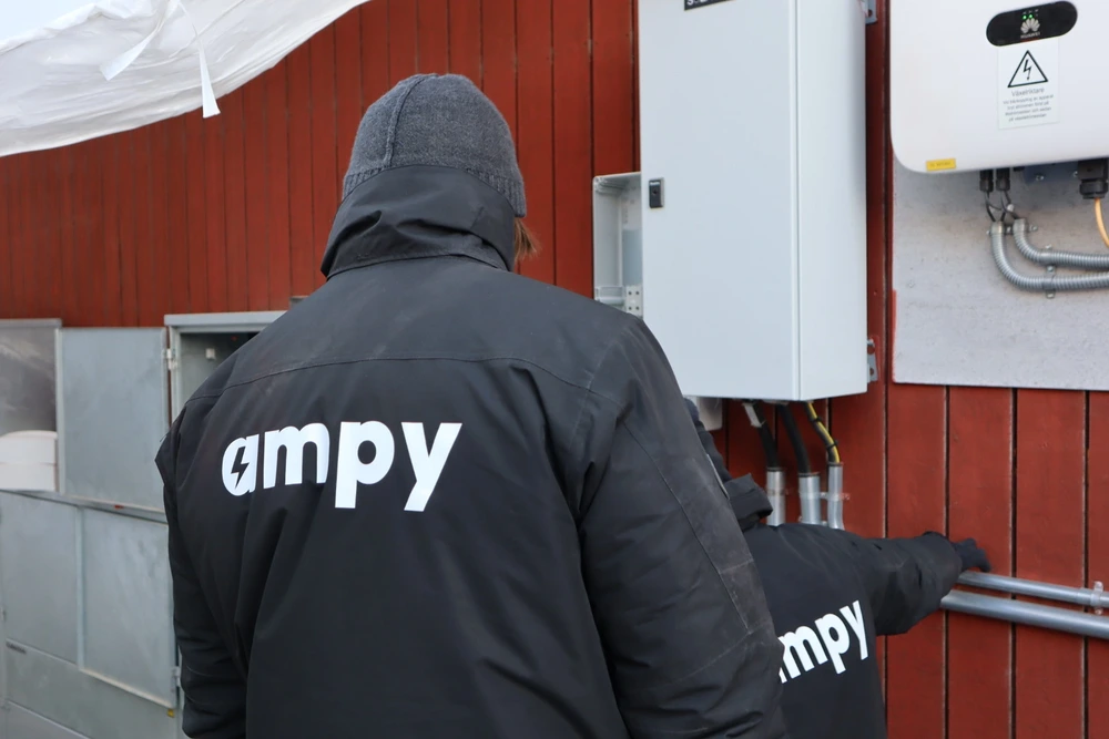 Elektrikern Felix, sedd bakifrån, som installerar en ny växelriktare på en vägg.