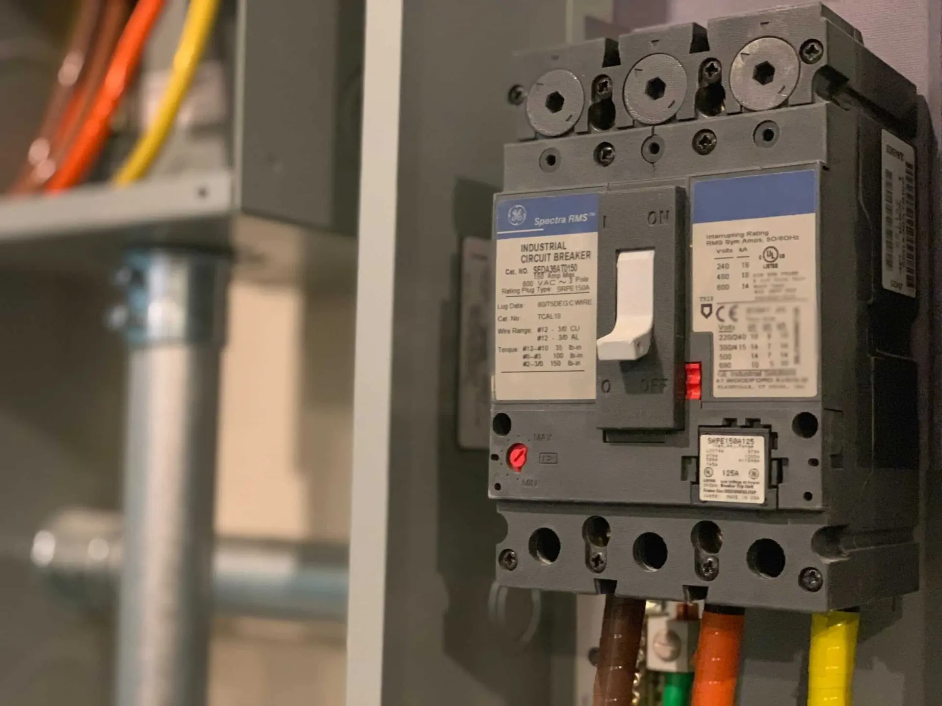 Närbild på en elektriker som ansluter kablar till en jordfelsbrytare i en elcentral.